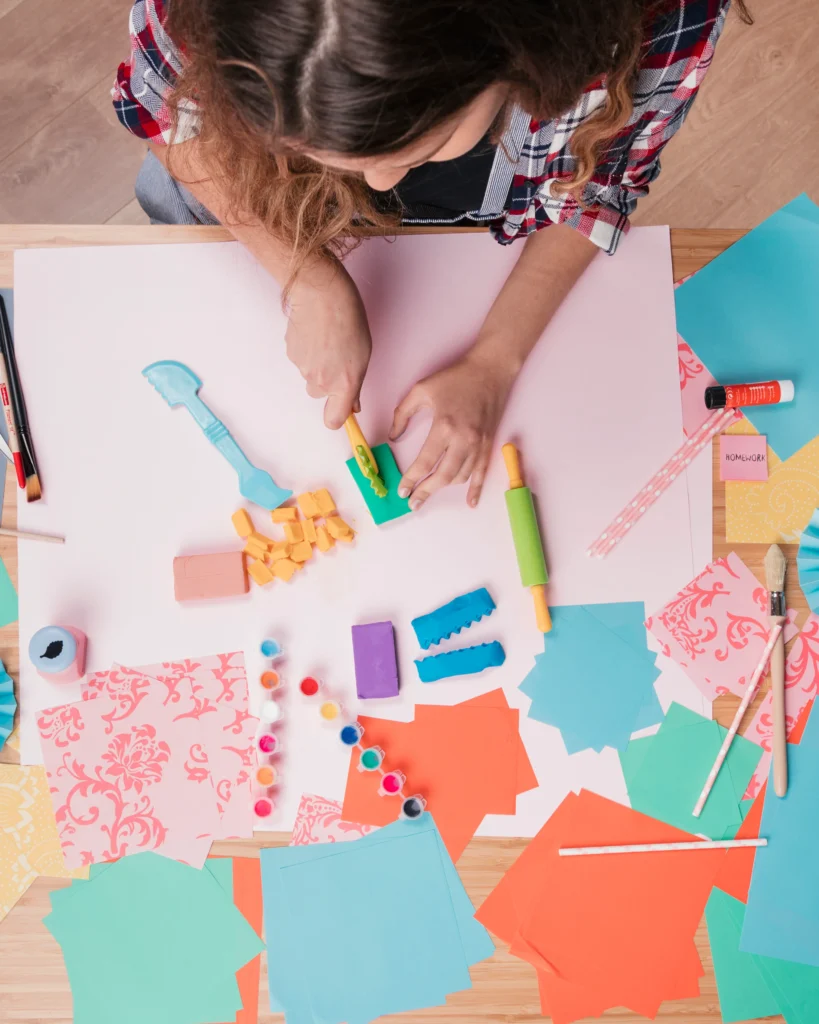top view woman cutting colorful clay paper