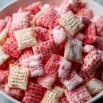 Fluffy Strawberry Shortcake Puppy Chow dessert in a bowl with strawberries